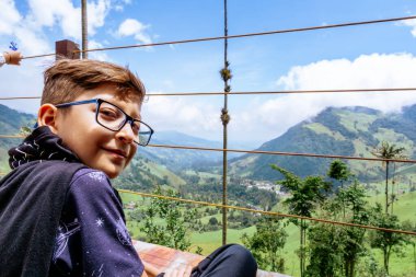 Kolombiya 'da Cocora Valley' de gözlüklü bir Latin çocuk yürüyüş yapıyor. Seyahat ve aile. Balmumu avuç içi.