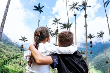 Dağların ve hurma ağaçlarının manzarasına bakan yumuşak kardeşler... Küçük gezginler. Çocuk Günü.