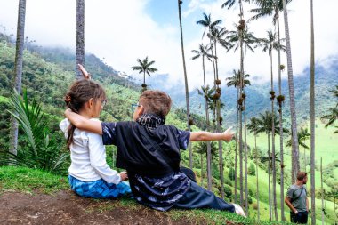 Dağların ve hurma ağaçlarının manzarasına bakan yumuşak kardeşler... Küçük gezginler. Çocuk Günü.