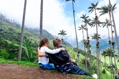 Dağların ve hurma ağaçlarının manzarasına bakan yumuşak kardeşler... Küçük gezginler. Çocuk Günü.