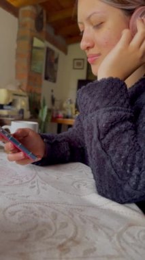 Kolombiyalı bir kadının kulaklıklı, pijamalı ve bir fincan kahve ya da çayla müzik dinlediği bir video.. 