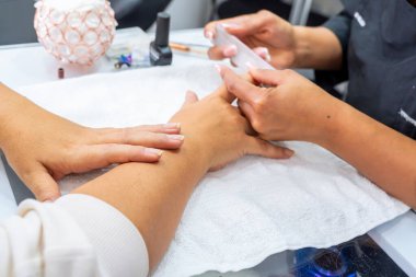 Mujer Latin Kolombiyalı en spa de uas. Manicurista haciendo limpieza y decacin de uas. Belleza y moda.