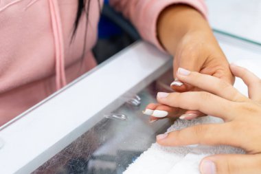 Mujer Latin Kolombiyalı en spa de uas. Manicurista haciendo limpieza y decacin de uas. Belleza y moda.