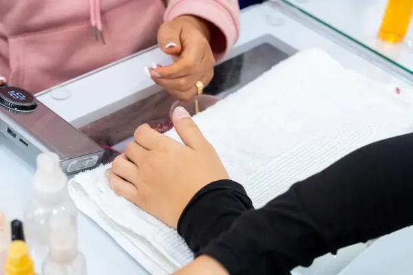 Mujer Latin Kolombiyalı en spa de uas. Manicurista haciendo limpieza y decacin de uas. Belleza y moda.
