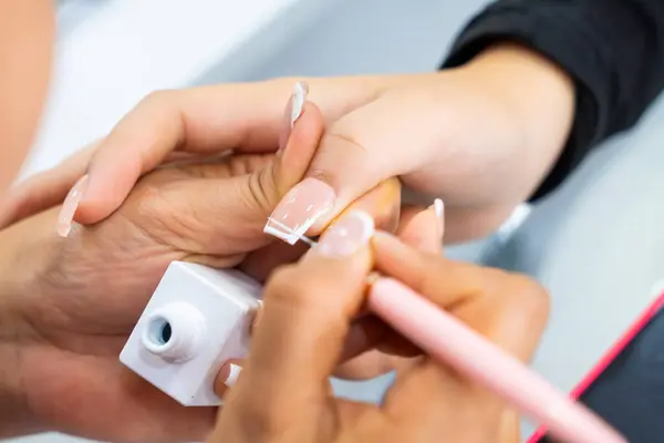 Mujer Latin Kolombiyalı en spa de uas. Manicurista haciendo limpieza y decacin de uas. Belleza y moda.