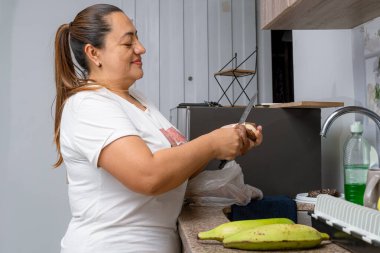 Kolombiyalı Latin anne, ailesi için evde yemek pişiriyor. Yemek yapmak kolay. Mutlu ev kadını.