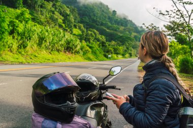 Latin bir gezgin ormanın ortasında haritasına bir yol ile bakıyor. Parlak ve soğuk renkler. Seyahat ve Kolombiya.