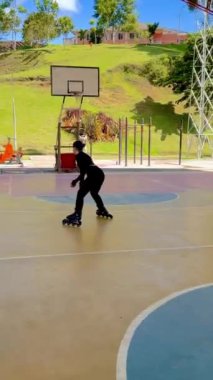 Güzel, genç, Kolombiyalı Latin bir kadının spor yaptığı, sahada kaymayı öğrendiği ve eğlendiği dikey bir video..