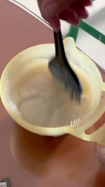 Bir kadının elinde koyu kahverengi saç boyama ürünleri karışımı bir plastik kalın