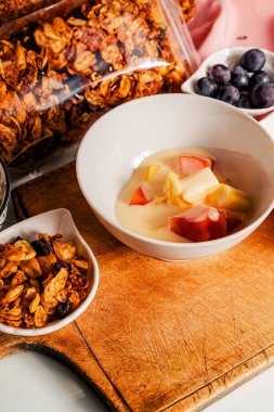 Ev yapımı granola ve meyvelerle karıştırılmış yoğurtlu sağlıklı kahvaltı: mango, papaya ve üzüm..