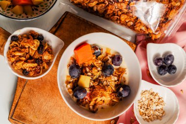 Ev yapımı granola ve meyvelerle karıştırılmış yoğurtlu sağlıklı kahvaltı: mango, papaya ve üzüm..