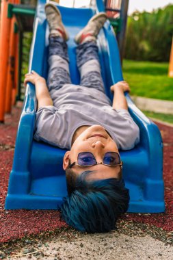 Kolombiyalı Latin kökenli mestizo 'nun fotoğrafı. Mavi saçlı, başı öne eğik bir şekilde kameraya bakıyor ve gülümsüyor..