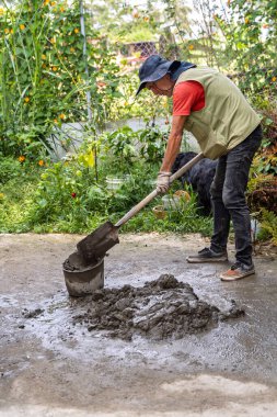 Ev yenileme projesine çimento ve inşaat suyu karıştıran yaşlı Kolombiyalı bir adam.