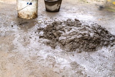 Evin yenilenmesi için zeminde çimento karışımı ve yanında kürek ve kova var.