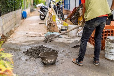 Ev yenileme projesine çimento ve inşaat suyu karıştıran yaşlı Kolombiyalı bir adam.
