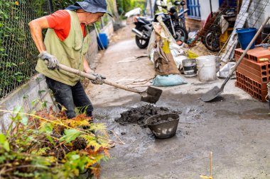 Ev yenileme projesine çimento ve inşaat suyu karıştıran yaşlı Kolombiyalı bir adam.