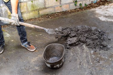 İnşaat için çimento karıştıran insan bacakları ev yenileme projesinde yanında kürek ve kova ile birlikte.