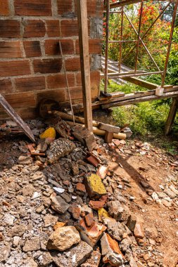 Kolombiya, Medellin yakınlarındaki dağların kırsal kesimindeki bazı duvarları yıktıktan sonra tuğla ve beton molozların yanında inşaat iskelesinin dikey fotoğrafı..