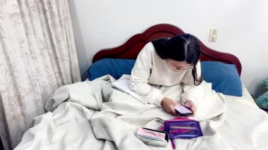 Koyu renk saçlı, siyah saçlı, yetişkin, siyah saçlı bir kadının yataktan kalkıp cep telefonunu aramaya odaklandığı bir video..