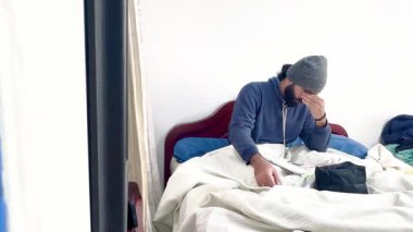 Yatağında kep ve gözlüklü yetişkin erkek Kolombiya mestizosu, defterinde matematik yapıyor ya da verimli bir şekilde çalışıyor..
