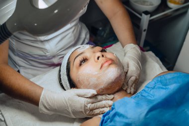 Güzellik merkezindeki genç Kolombiyalı melez kadının fotoğrafı. Yüz temizleme ameliyatı yaptırıyor ve yüz derisini yüzüyor..