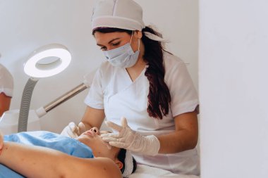 Güzellik merkezindeki genç mestiza Kolombiyalı bir kadının yüz temizleme tedavisini tamamlamak için yüzüne sürdüğü fotokopi aralıklı fotoğrafı..