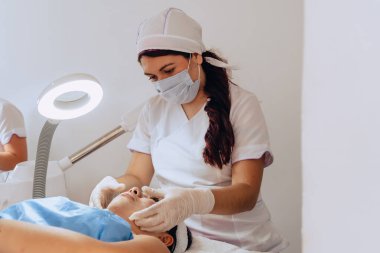 Güzellik merkezindeki genç mestiza Kolombiyalı bir kadının yüz temizleme tedavisini tamamlamak için yüzüne sürdüğü fotokopi aralıklı fotoğrafı..