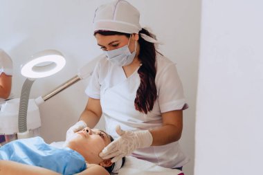 Güzellik merkezindeki genç mestiza Kolombiyalı bir kadının yüz temizleme tedavisini tamamlamak için yüzüne sürdüğü fotokopi aralıklı fotoğrafı..