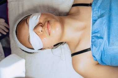 Genç bir Kolombiya mestizasının yatay olarak çekilmiş yüzü nemlendirici bir jelin yüzüne girmesini beklerken gözleri kaplıcayla kaplıydı..