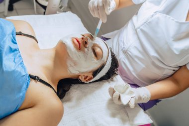 Cildiyecinin, Kolombiyalı genç bir Latin kadının yüz temizleme kliniğine çamur maskesi takarken çekilmiş fotoğrafı.