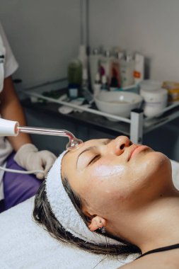 Güzellik merkezindeki genç Kolombiyalı bir kadının fotoğrafı. Yüzü temizleniyor ve mikroakım cihazıyla arınma aşamasına geçiyor..