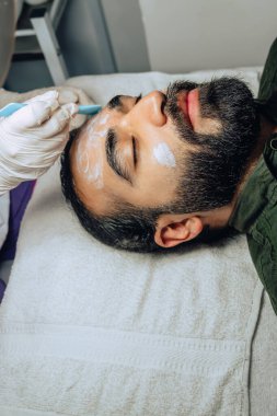 Sakallı yetişkin bir Kolombiyalı mestizo adam için profesyonel deri yüzme, nemlendirici ve yüz temizleme tedavisinin uzay fotokopisi..