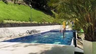 Risaralda, Kolombiya 'daki kırsal otelin havuzuna dalış yapan bir adam güneşli bir günde doğa tarafından çevrelenmiş, sıcak hava sırasında yatay formatta yakalanmış.