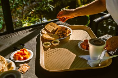Santuario, Risaralda, Kolombiya 'daki açık hava masasında çırpılmış yumurta, tost, papaya, sos ve içecek ile birlikte düşük açılı kahvaltı tepsisini kapat.