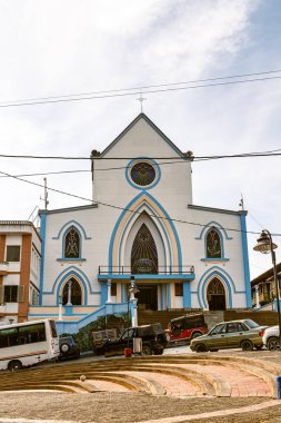 Gündüz vakti Apia, Risaralda, Kolombiya 'da renkli kemerli pencereli ve beyaz cepheli Apia de Viento kilisesinin alçak açılı yan görüntüsü
