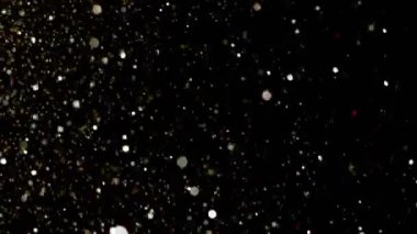 Yavaş çekimde ışıldayan bir patlama Bokeh arka planında parlayan sönmüş ışıltılı toz makrosuyla yakın çekim. Yüzen altın parıltılar. Parlayan Parçacıklar. Üst üste