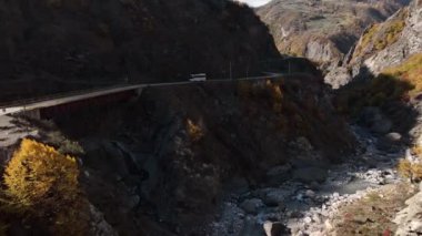 Bir dağın yamacındaki köprüden geçen otobüsün hava görüntüsü