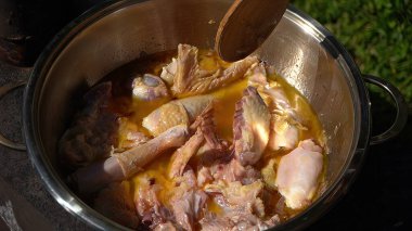 Ateşin üstünde bir tencerede tavuk eti hazırlıyorum.