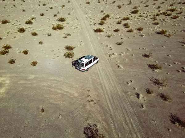 Aerial view of self converted camper van recreational vehicle driving on a dry lake bed in the desert of southern nevada United States with solar panels and bikes mounted to the rv van life rig.
