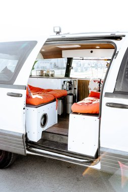 Minibüse dönüşmüş eski bir karavanı aydınlatmak için güzel, parlak bir ışık giriyor. Vanlife eğlence aracının turuncu koltuk minderleri, lekeli çatısı ve minibüs fabrikası var..