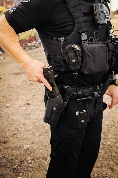 Vertical image of white male caucasian police officer reaching down and places hand on his weapon hand gun and pulls gun out of holster on hip. Close up shot. No head.