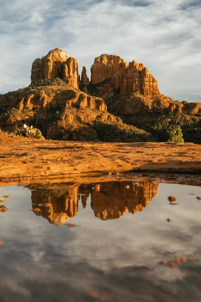 Red rock cathedral rock illuminated during sunset with reflection on small natural pool in the american southwest of Sedona Arizona in Yavapai County after a heavy rain fall the night before.