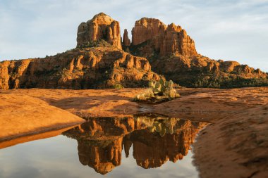 Red rock cathedral rock illuminated during sunset with reflection on small natural pool in the american southwest of Sedona Arizona in Yavapai County after a heavy rain fall the night before.