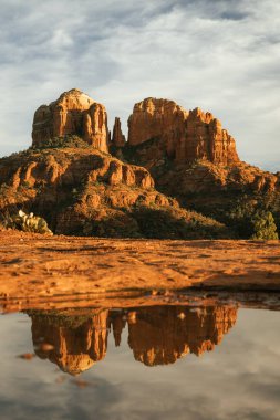 Red rock cathedral rock illuminated during sunset with reflection on small natural pool in the american southwest of Sedona Arizona in Yavapai County after a heavy rain fall the night before.