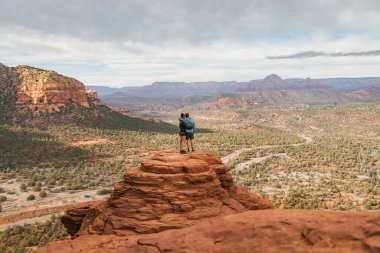Genç heteroseksüel çift yürüyüşçüleri, Sedona Arizona 'daki Hindistan cevizi ulusal ormanında Bell Rock' ta birbirlerine sarılıyorlar.