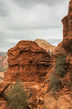 Man hiker standing on Bell Rock with incredible views within coconino national forest in Sedona Arizona USA against white cloud background.