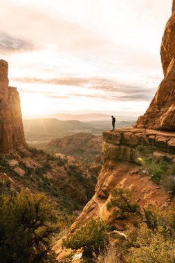 Genç adam gün batımında Katedral Rock Sedona 'da dramatik uçuruma bakıyor.