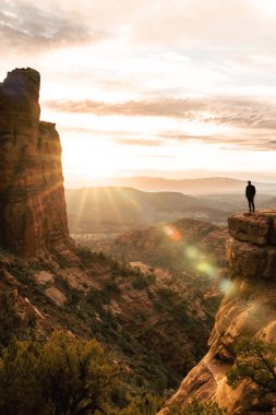 Gün batımında Katedral Rock Sedona 'da genç adam ve güneş parlıyor.