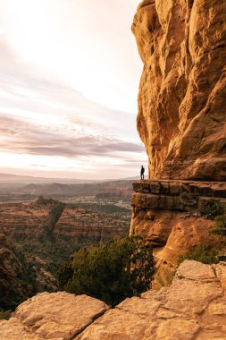 Adam Katedral Rock 'tan dramatik gün batımı manzarasına bakıyor..