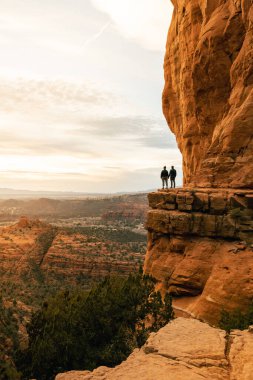 Genç heteroseksüel çift Sedona 'daki Katedral Rock' tan dramatik gün batımında el ele tutuşuyorlar..